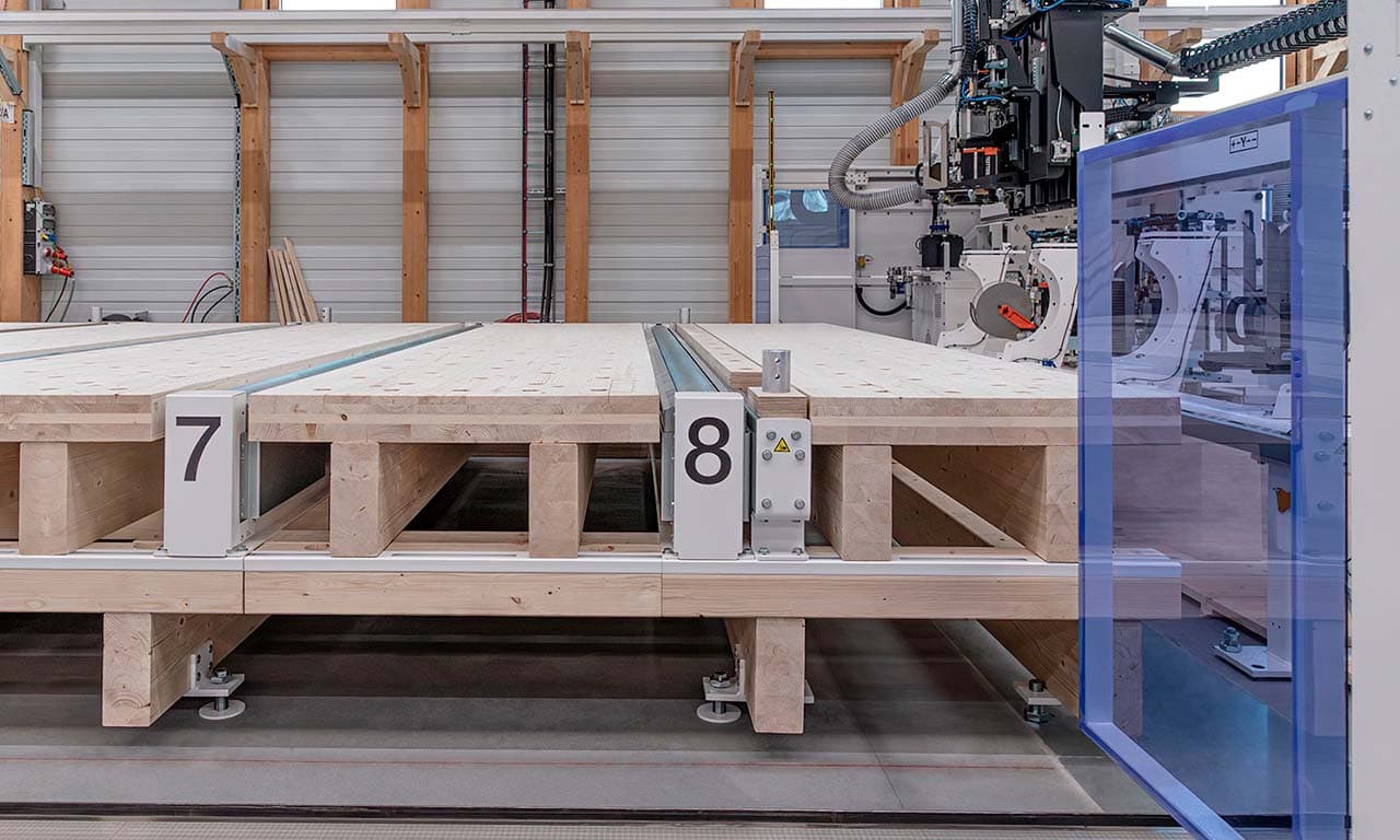 Industrial pallet staging area with numbered stations 7 and 8 and a robotic machine enclosed in a blue safety shield on the right.
