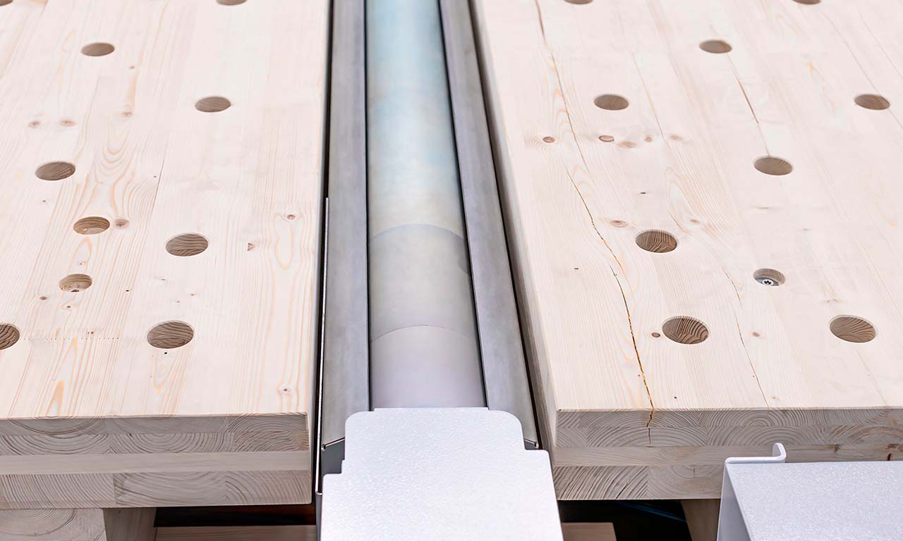 Close-up of a wooden workbench with holes and a central metal roller mechanism between two planks? (informative)