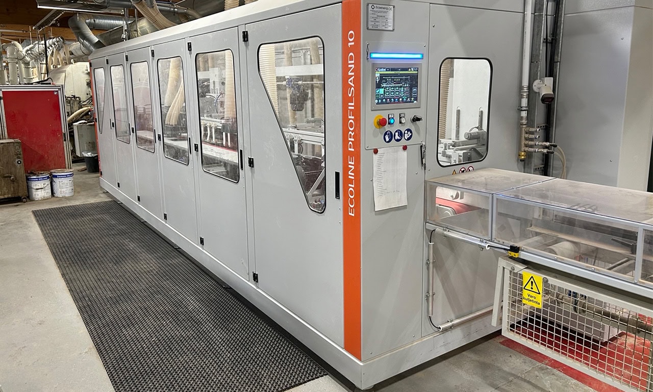 Long gray automated production line with safety doors and an orange vertical stripe labeled ECOLINE PROFISLAND 10 in a manufacturing plant control panel visible